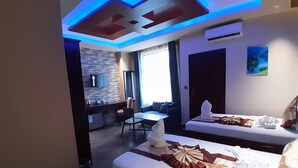 A hotel room with a bed, a small table, a sofa, a TV, and a bathroom. - MAZOLA DIAMOND HOTEL (Dar es Salaam)