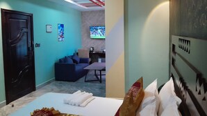 A hotel room with a bed, a sofa, a television, and a door. - MAZOLA DIAMOND HOTEL (Dar es Salaam)