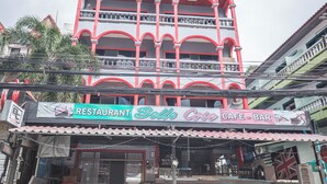 Un edificio de varios pisos con un letrero llamativo que dice 'Restaurant Belle Case Cafe-Bar'.