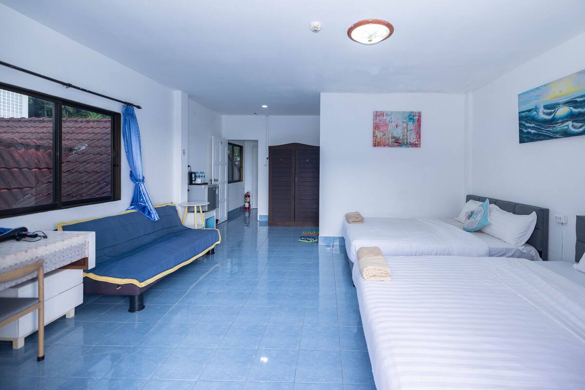 Habitación de hotel con cama, sofá, escritorio y ventana con vistas al exterior.