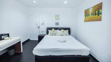 A hotel room with a bed, a desk, a chair, a trash bin, and a painting on the wall.