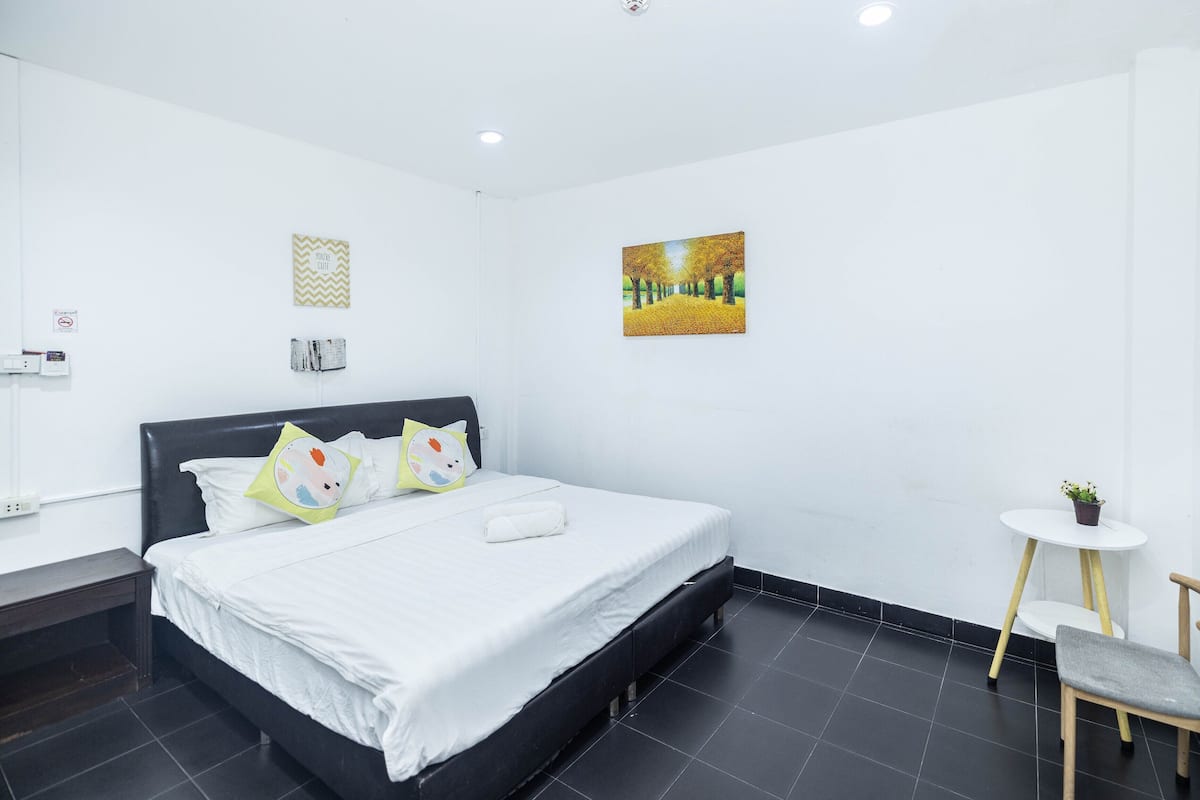 Una habitación de hotel moderna con una cama grande, una mesita redonda y una silla.