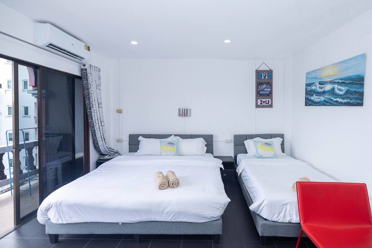 Habitación de hotel con dos camas, una silla roja y un cuadro del océano.