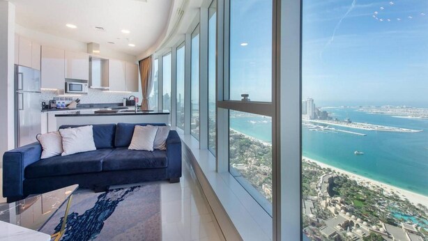 A modern living room with a large window offering a view of a coastal cityscape. - GLOBALSTAY. Avani Palm View (Dubai)