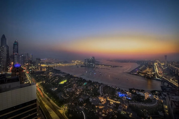 A cityscape at dusk with illuminated buildings, a river, and a bridge. - GLOBALSTAY. Avani Palm View (Dubai)