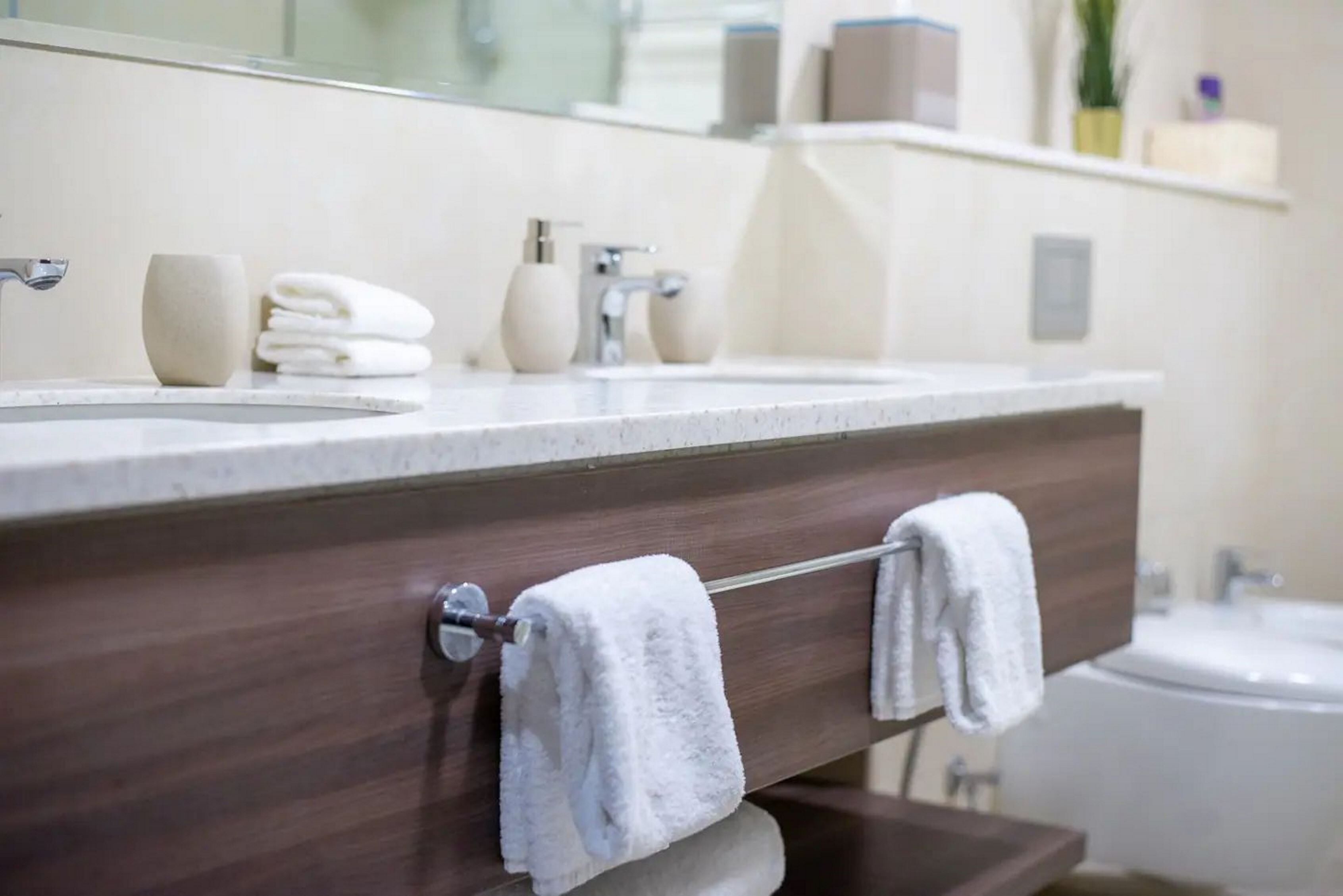 A bathroom with a double sink, a mirror, and a towel rack.