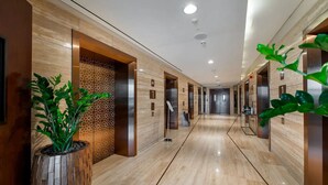 A modern hotel lobby with a marble floor, wooden accents, and a geometric patterned wall. - GLOBALSTAY. Avani Palm View (Dubai)