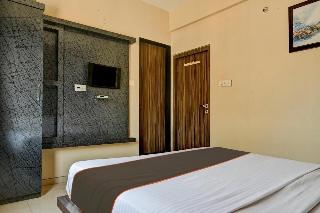 Una habitación de hotel con una cama, un televisor montado en una pared texturizada y dos puertas de madera.