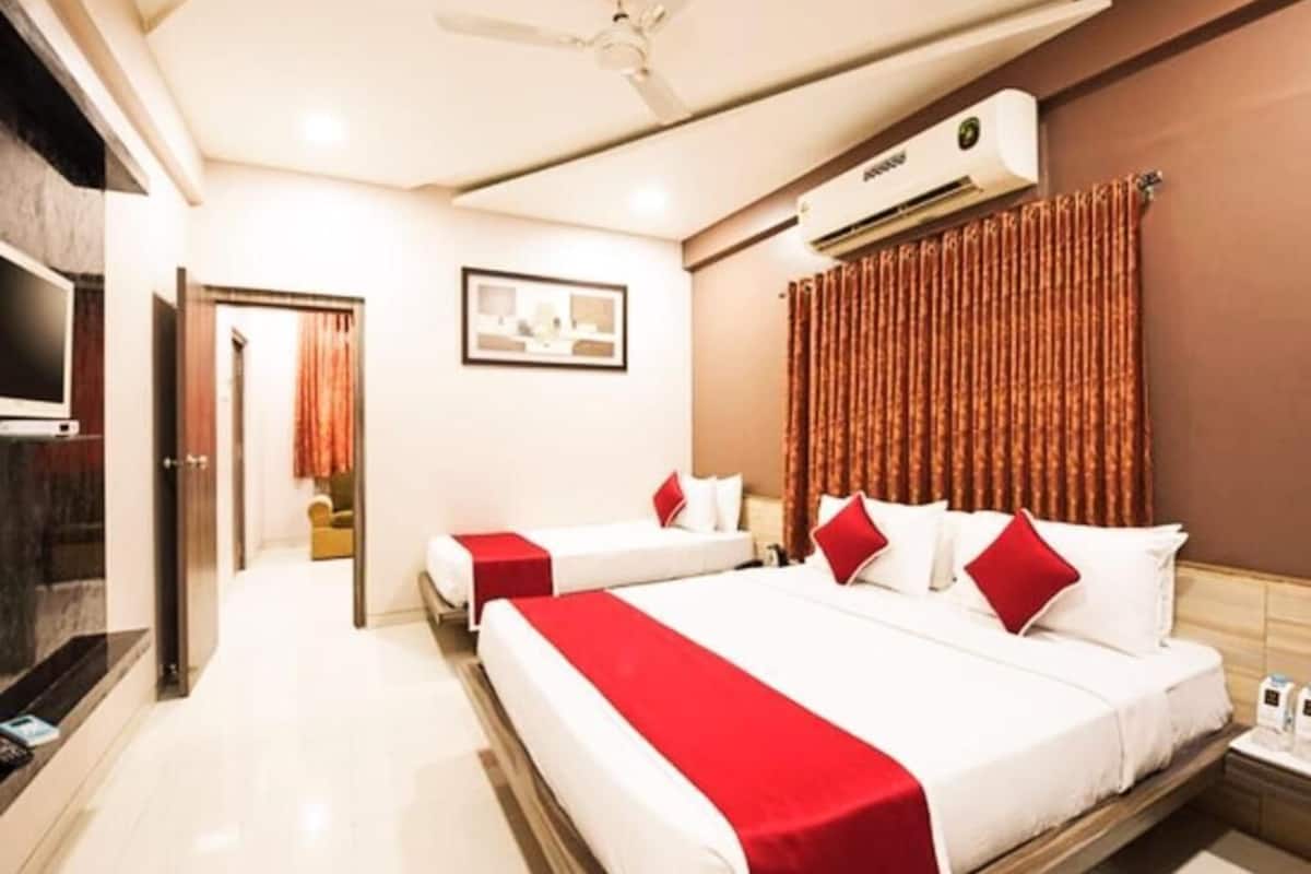 A hotel room with two beds, a ceiling fan, an air conditioning unit, and a television.