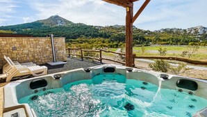 A hot tub with a mountain view, stone wall, and wooden deck chairs. - Vacation home Iva by Interhome (Karlobag)