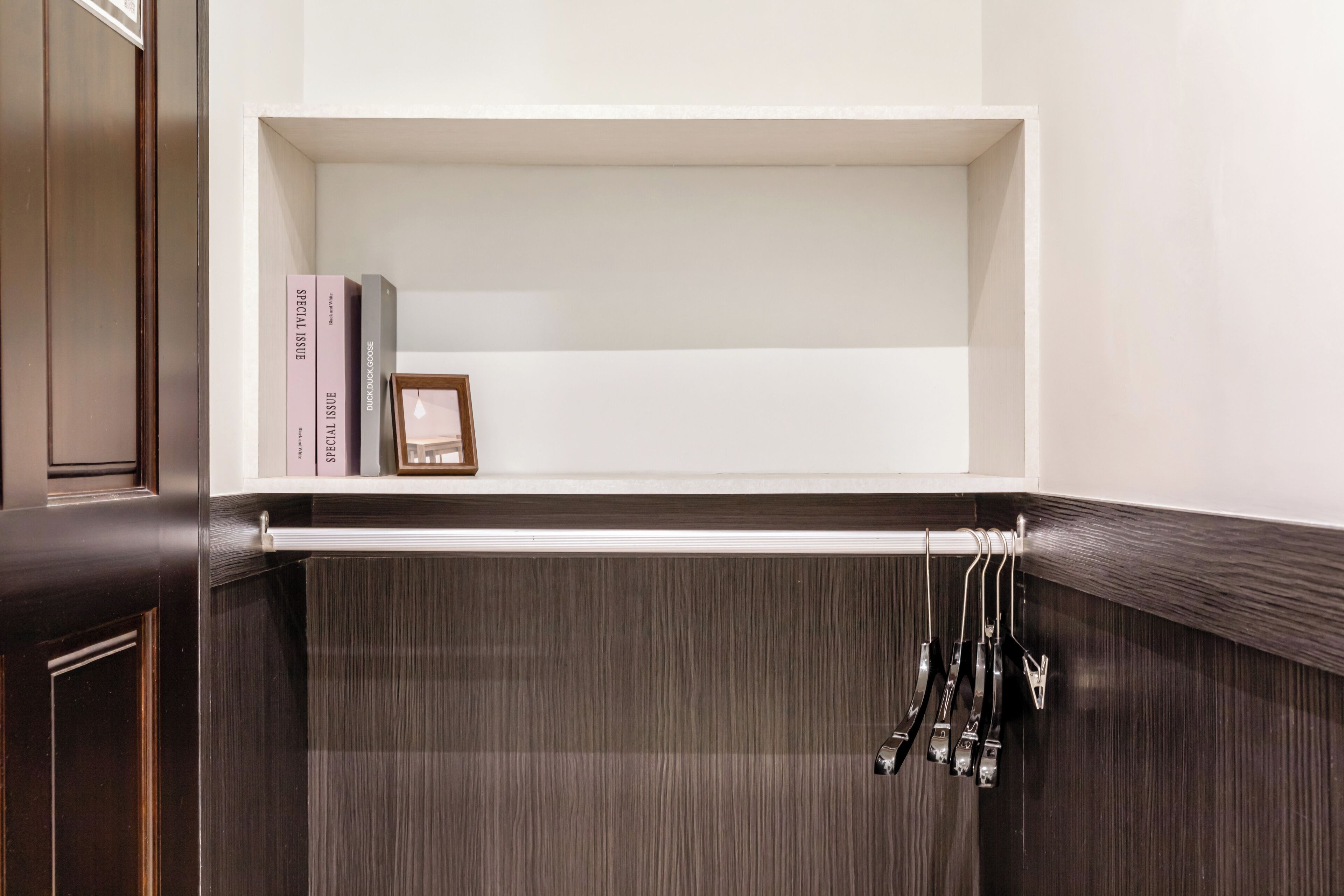 Une salle de bain avec un meuble-lavabo en bois, un porte-serviettes et une étagère contenant des livres et un tableau encadré.