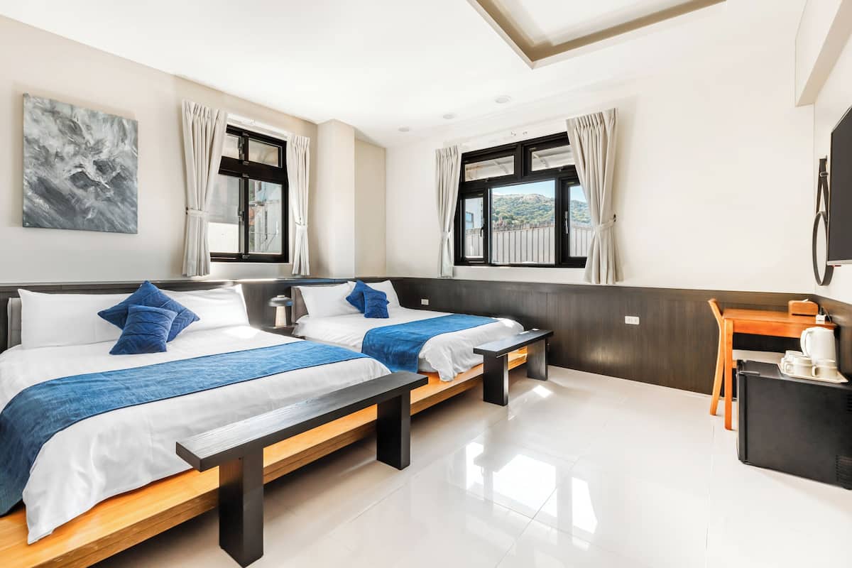 Una habitació d'hotel amb dos llits, un escriptori i una televisió.