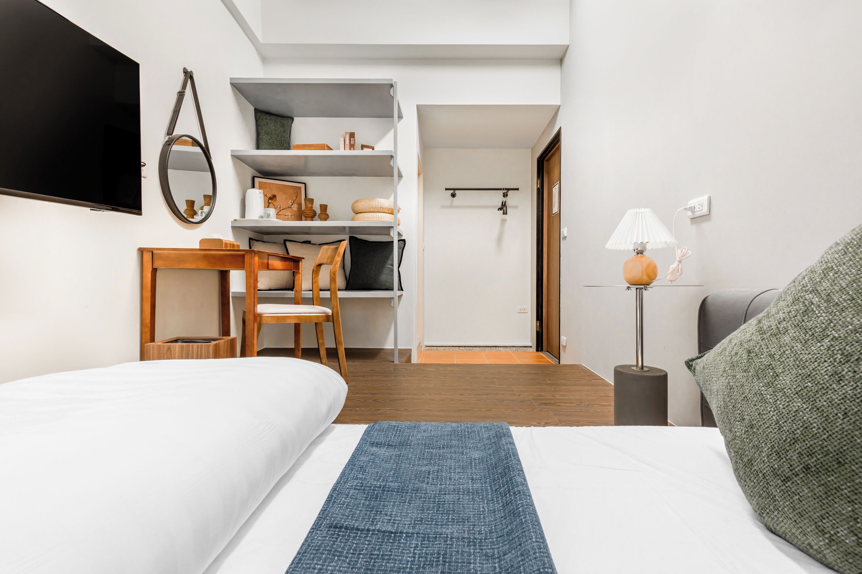 Una habitación de hotel moderna con cama, escritorio, silla y armario.