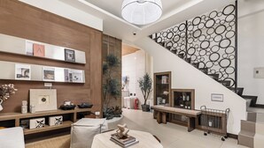 A modern living room with a wooden accent wall, a staircase with a circular pattern, and a bench with magazines. - Harmony Easy Stay (New Taipei City)