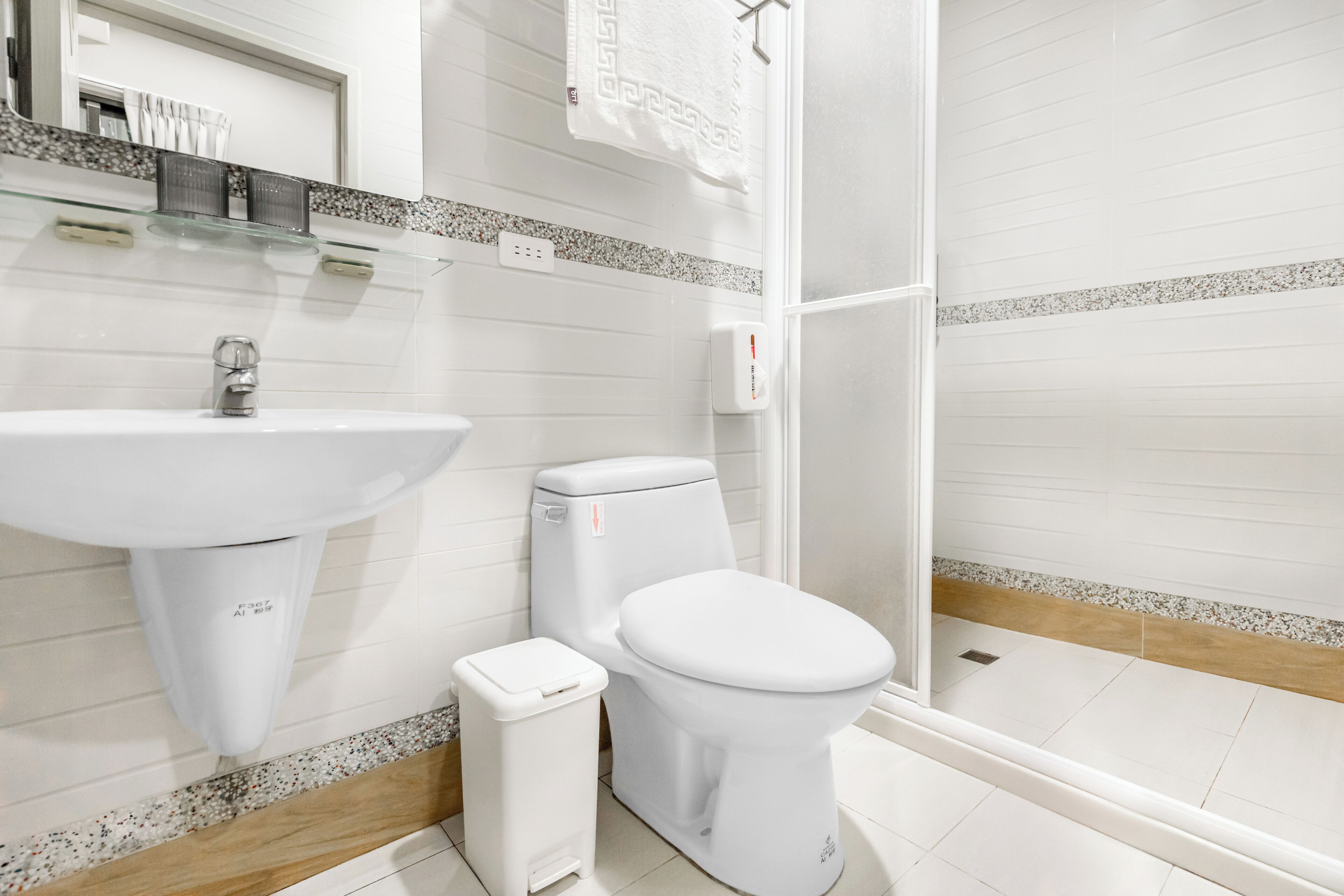 A modern bathroom with a white sink, toilet, and shower.