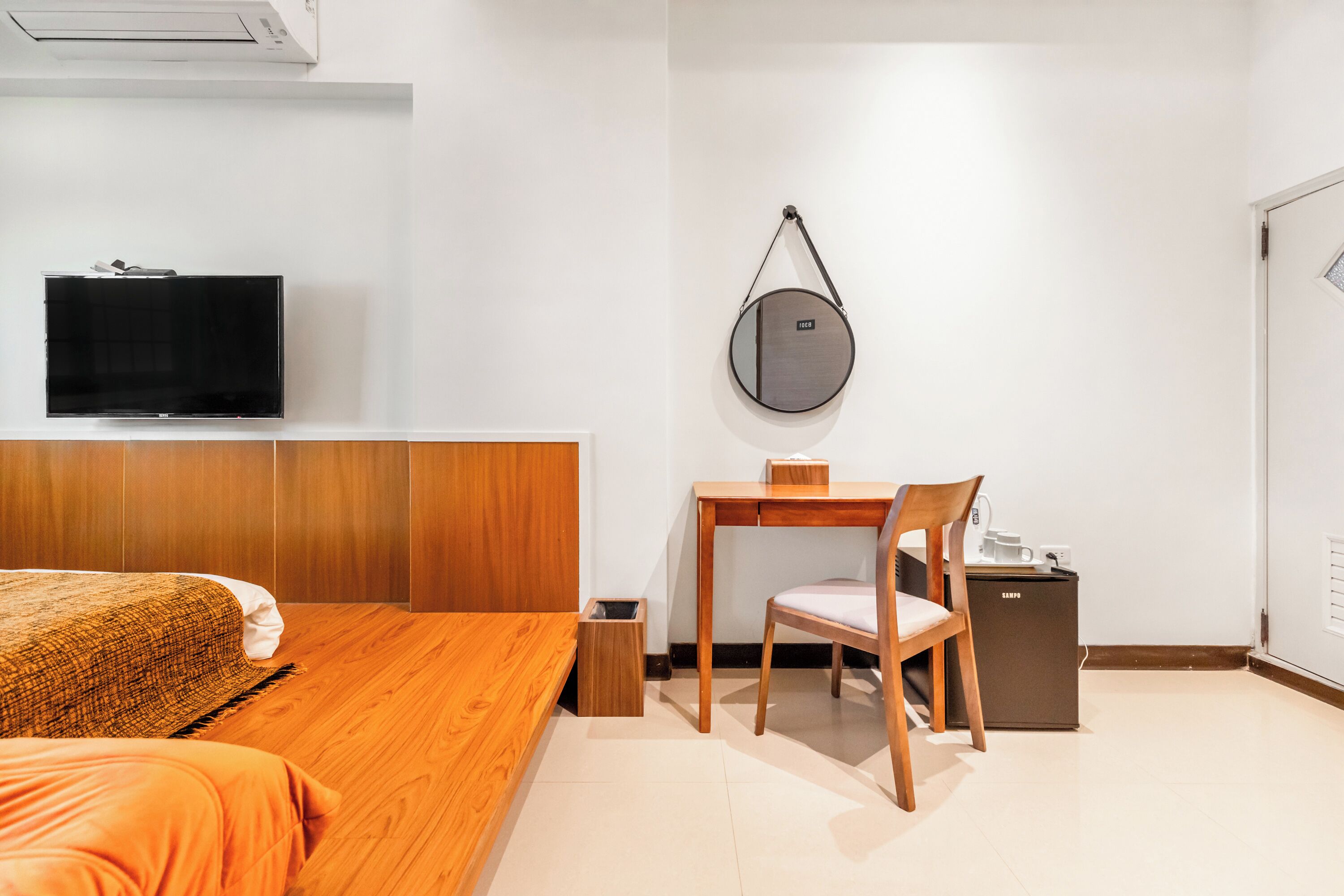 A hotel room with a bed, a desk, a chair, a TV, and a small cabinet.