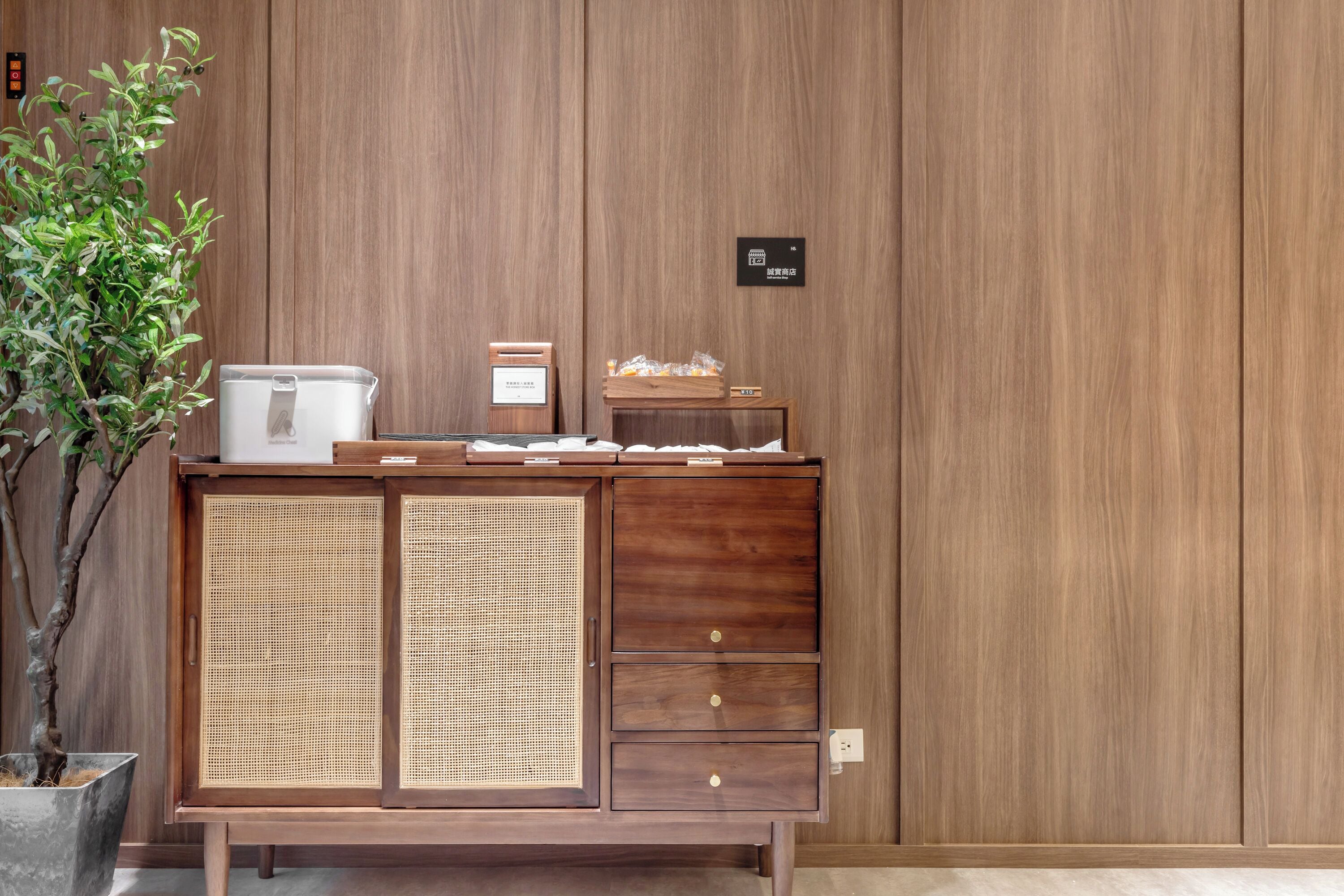 Un mueble de madera con un panel frontal tejido, una planta pequeña y un cartel que indica el número de habitación 124.