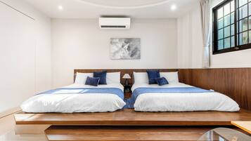 Quarto moderno com cama central, mesa de cabeceira pequena, ar condicionado fixado na parede e janela com cortinas.