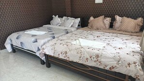 Un lit double avec une literie à motifs floraux, une table de chevet et un mur orné d’un motif en losanges.