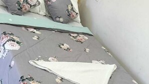 Un lit avec une literie à motifs floraux, des oreillers et une couverture.