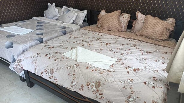 Un lit double avec une couvre-lit à motifs floraux et deux paires d’oreillers.