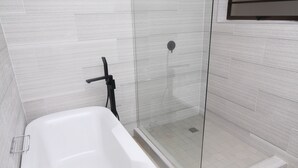 A modern bathroom with a freestanding bathtub, a glass-enclosed shower, and tiled walls. - The Oak Tree House (Gaborone)