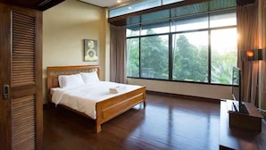 A spacious bedroom with a large window, a wooden bed, and a nightstand. - Khaoyai Valley 2 (Pak Chong)