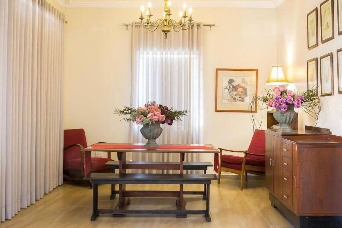 Uma sala de jantar com mesa de madeira, bancos, um candelabro e arranjos florais.