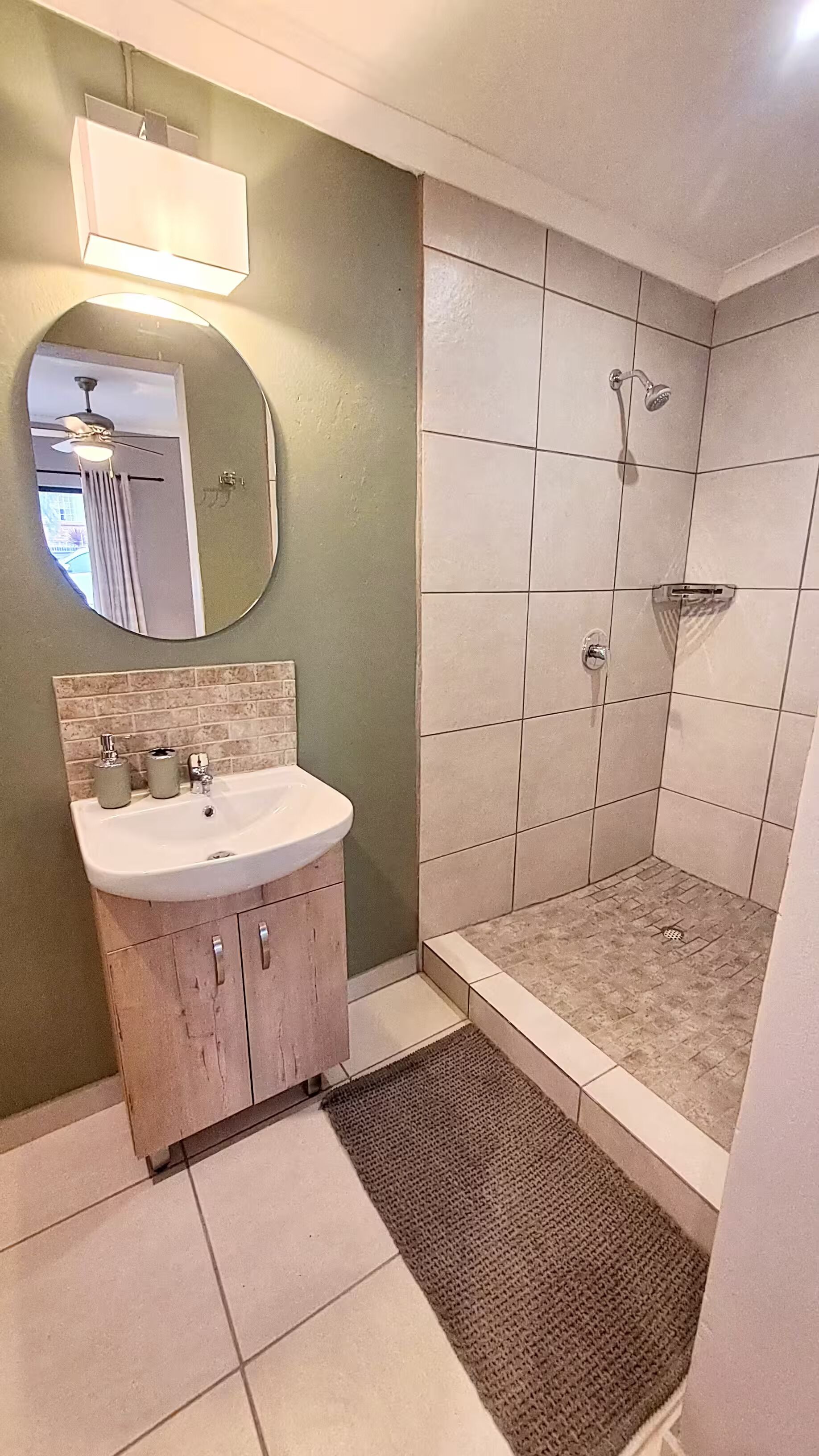 A bathroom with a sink, mirror, and shower.