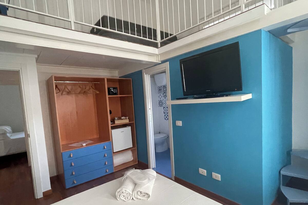 Une chambre à coucher comprenant un lit, une armoire, une télévision et une salle de bain.