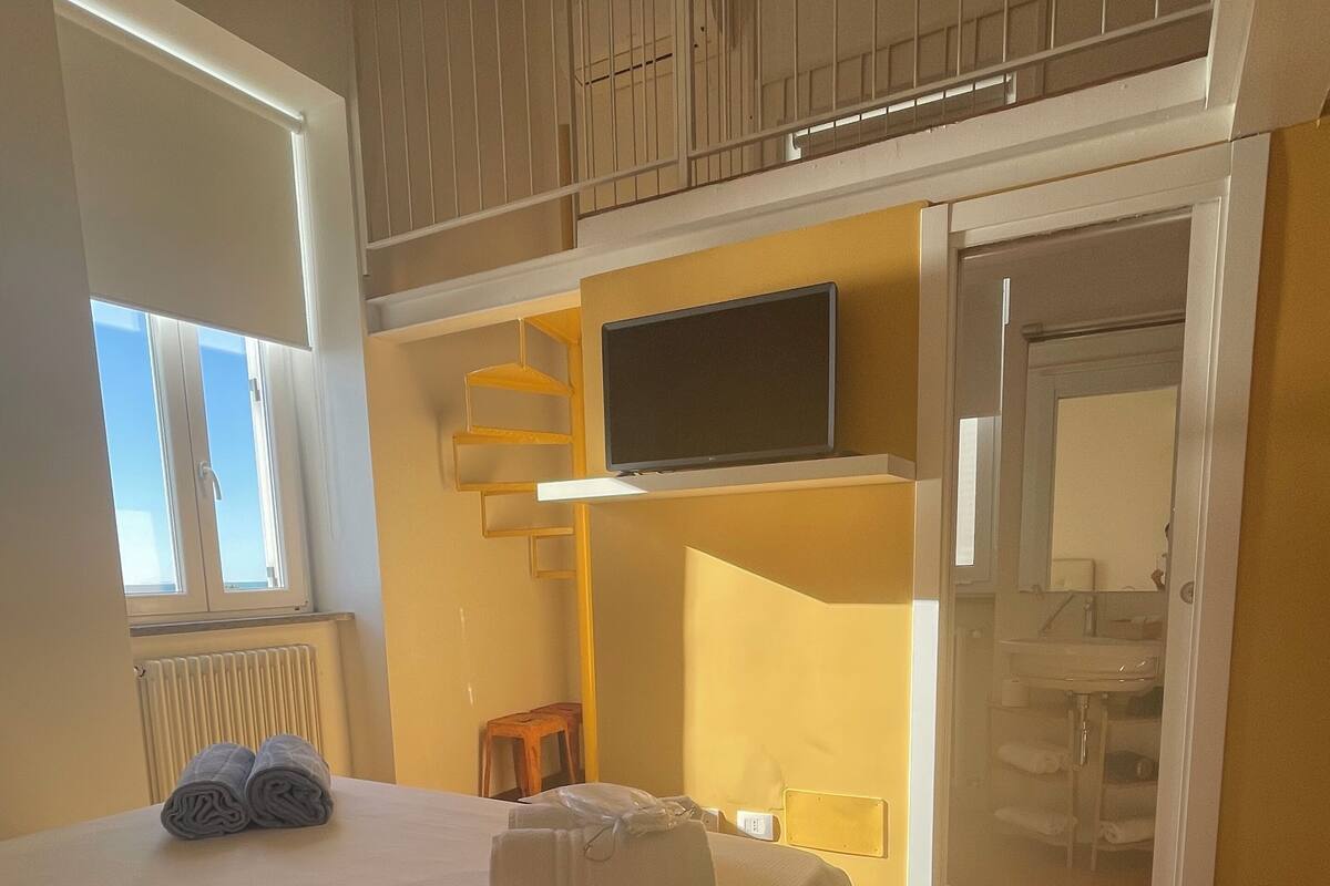 Une chambre d’hôtel avec un lit, un téléviseur fixé au mur, une armoire et une fenêtre avec des stores.