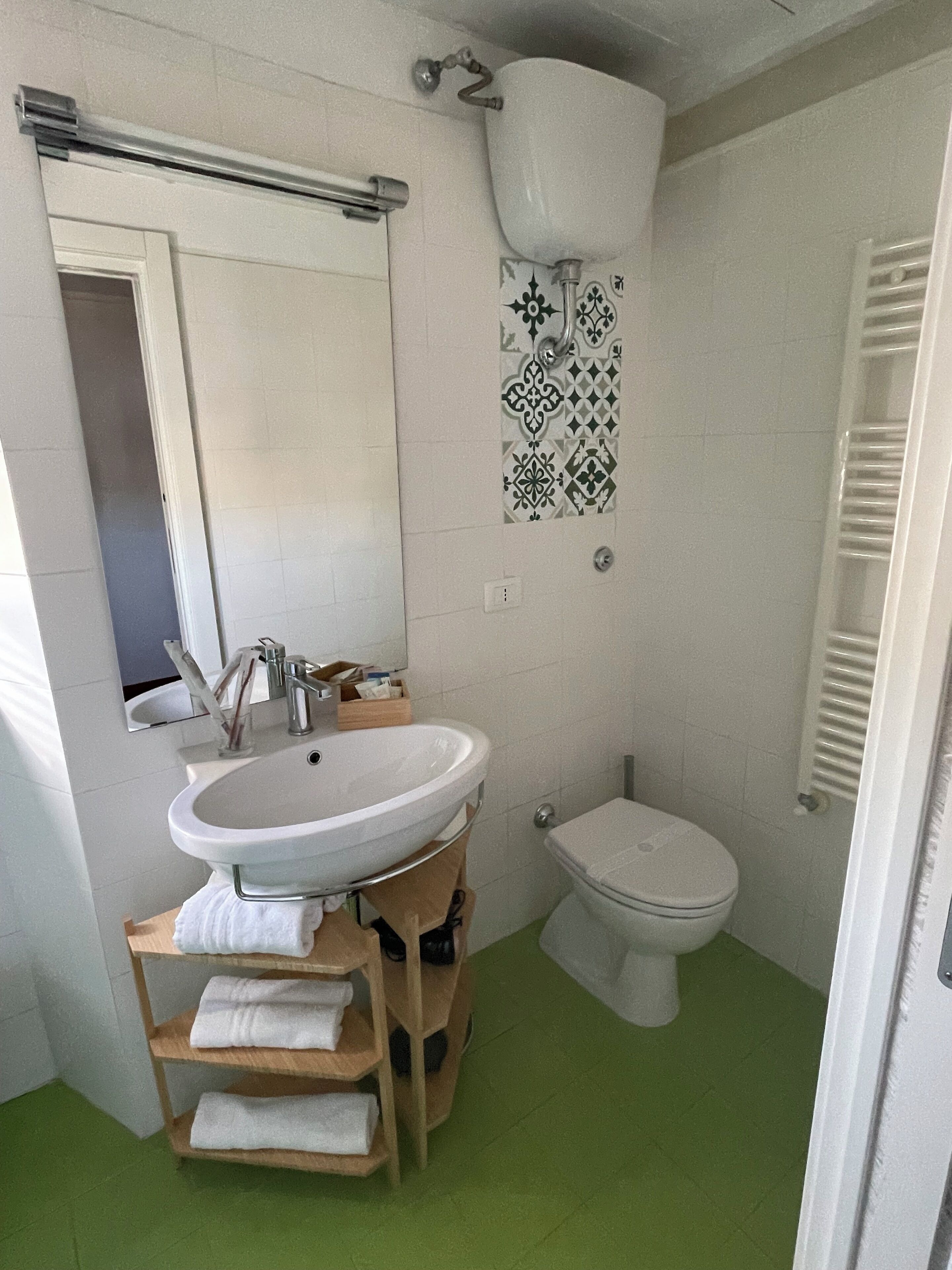 Une salle de bain avec un lavabo blanc, des toilettes et un sol vert.