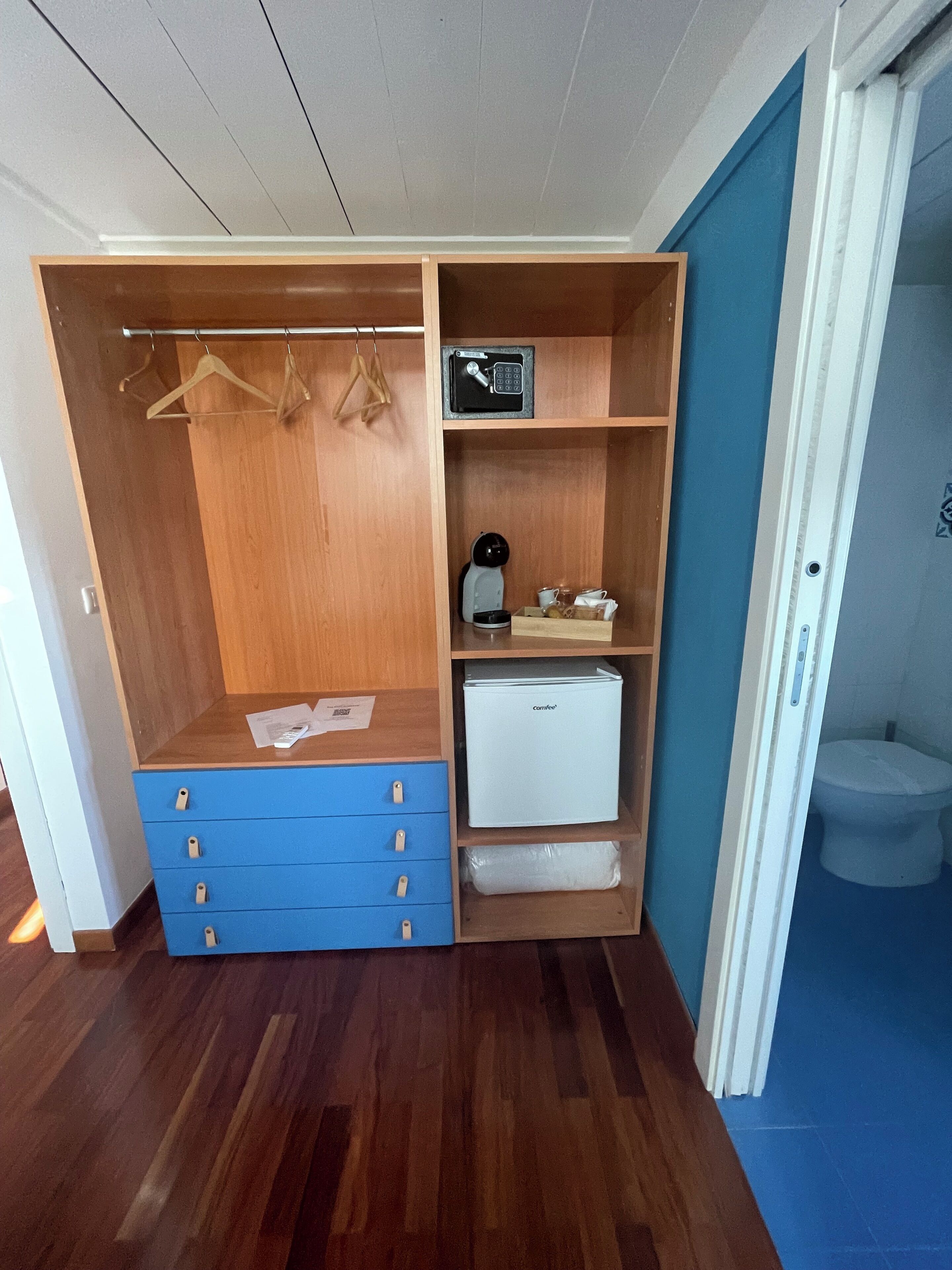 Un dressing avec des étagères en bois, une machine à café et un petit réfrigérateur.