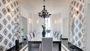 A modern dining room with a long table, white chairs, and a chandelier.