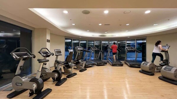Un gimnasio con cintas de correr, elípticas y máquinas de pesas.