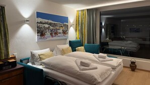 A hotel room with a bed, a desk, a chair, a painting, and a window with curtains. - Well-kept holiday apartament house in a prime location in St. (St. Moritz)