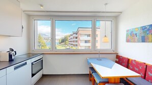 A compact kitchen with a built-in oven and a coffee machine, a bench at the window, and a view of a residential area. - Well-kept holiday apartament house in a prime location in St. (St. Moritz)