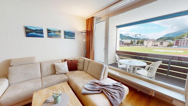 A modern living room with a sofa, a coffee table, and a balcony with a view of a mountainous landscape. - Well-kept holiday apartament house in a prime location in St. (St. Moritz)