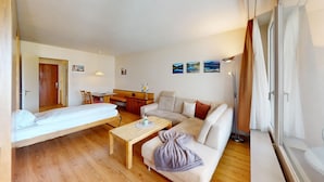 A compact hotel room with a bed, a sofa, a small table, a desk, and a kitchenette. - Well-kept holiday apartament house in a prime location in St. (St. Moritz)