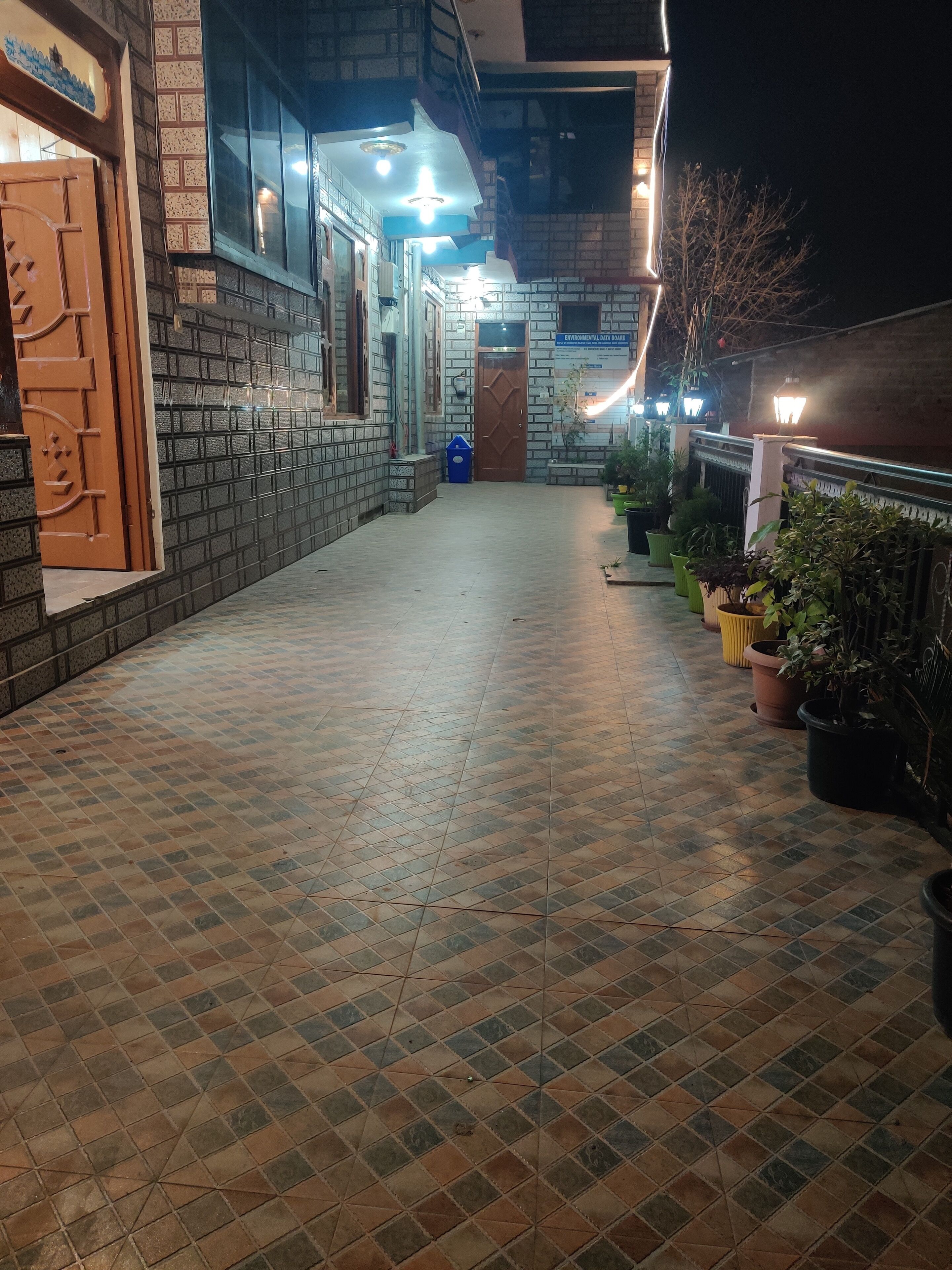 A tiled walkway leading to a building with a wooden door and a signboard.