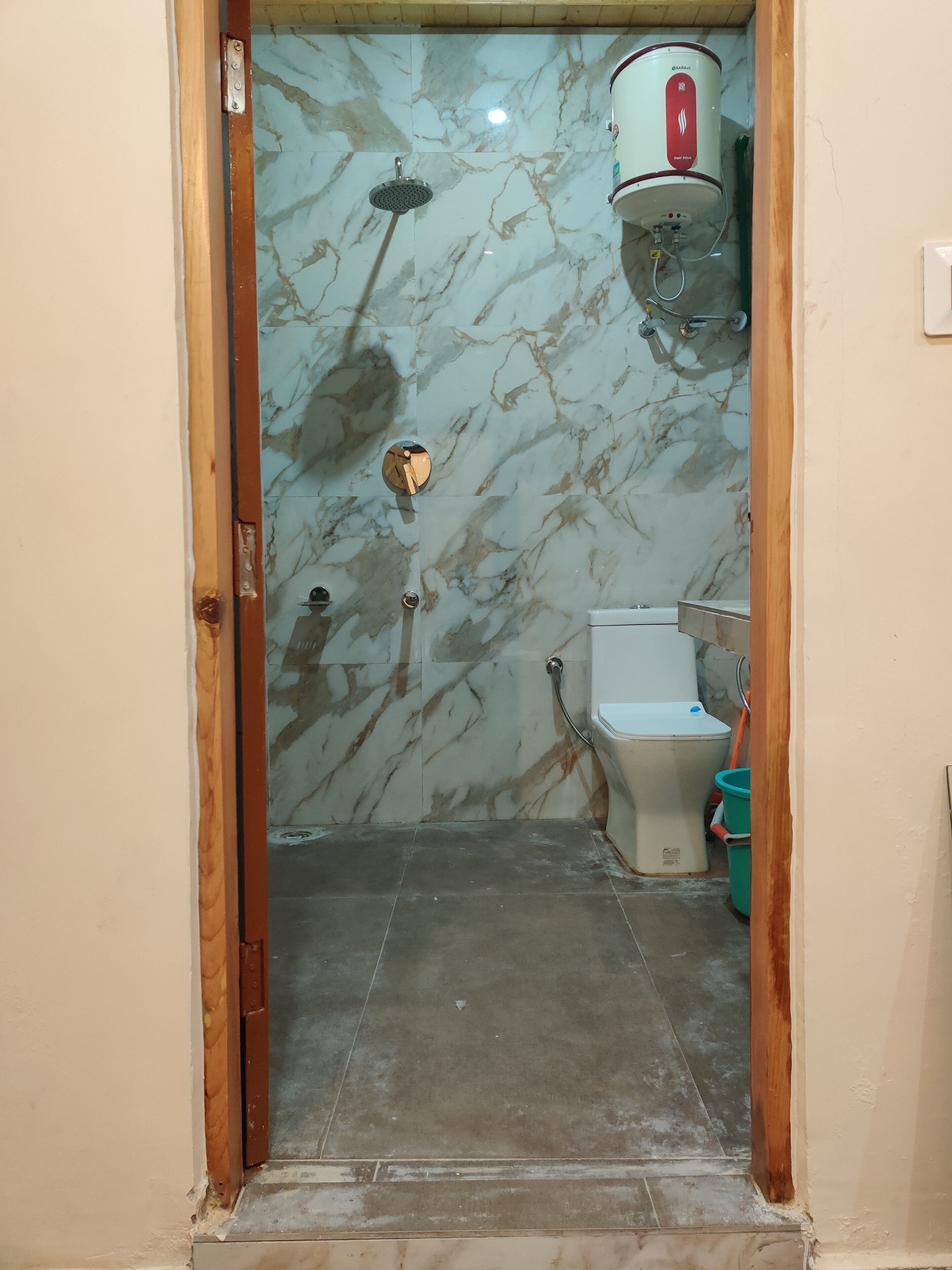 A bathroom with a marble wall, a shower, a toilet, and a water heater.