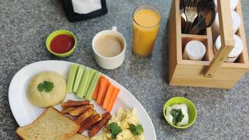 A breakfast plate with toast, scrambled eggs, and vegetables, a glass of orange juice, a cup of coffee, and a box of utensils.