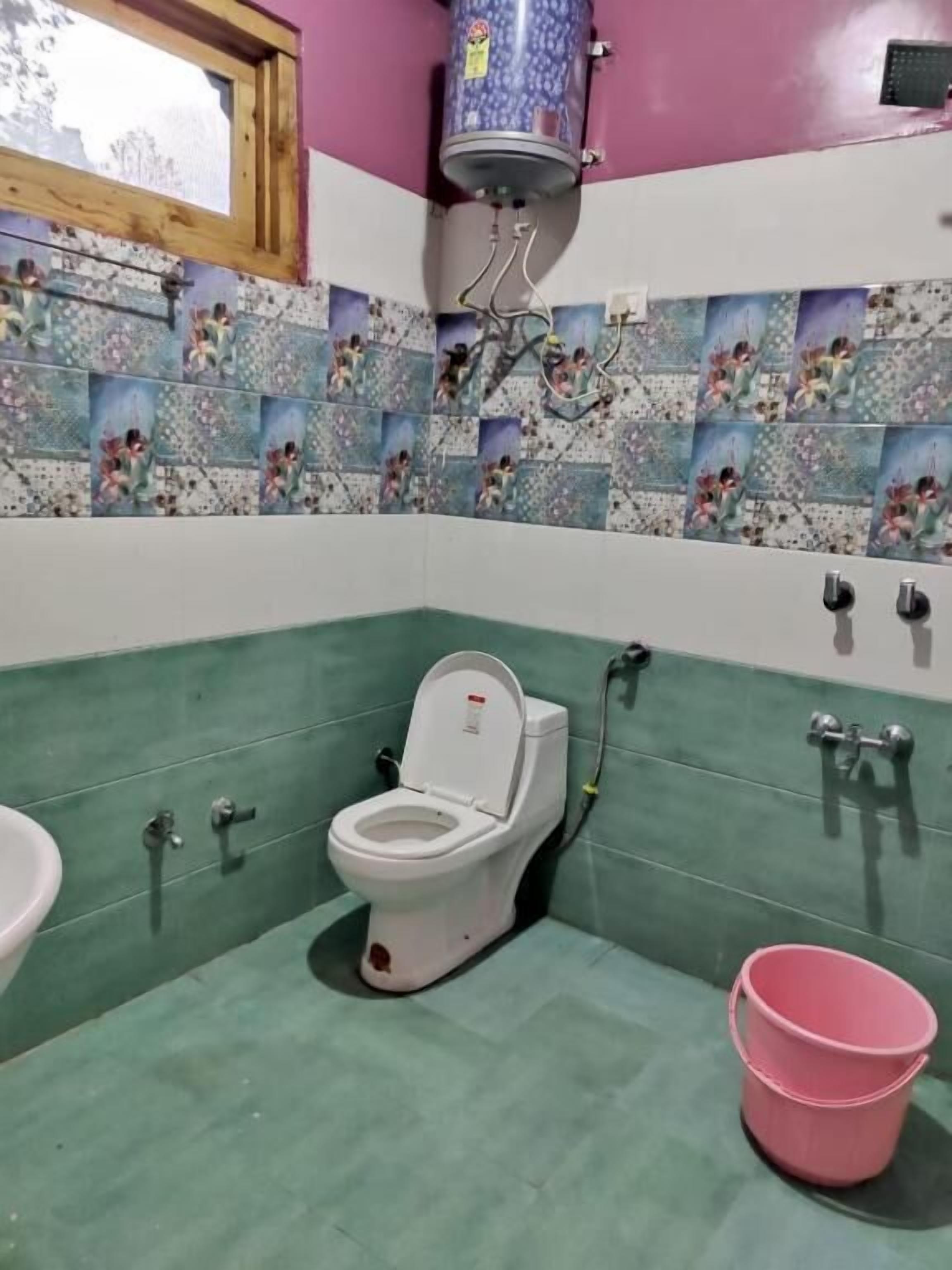 Ein Badezimmer mit Toilette, Waschbecken und einem rosa Eimer.