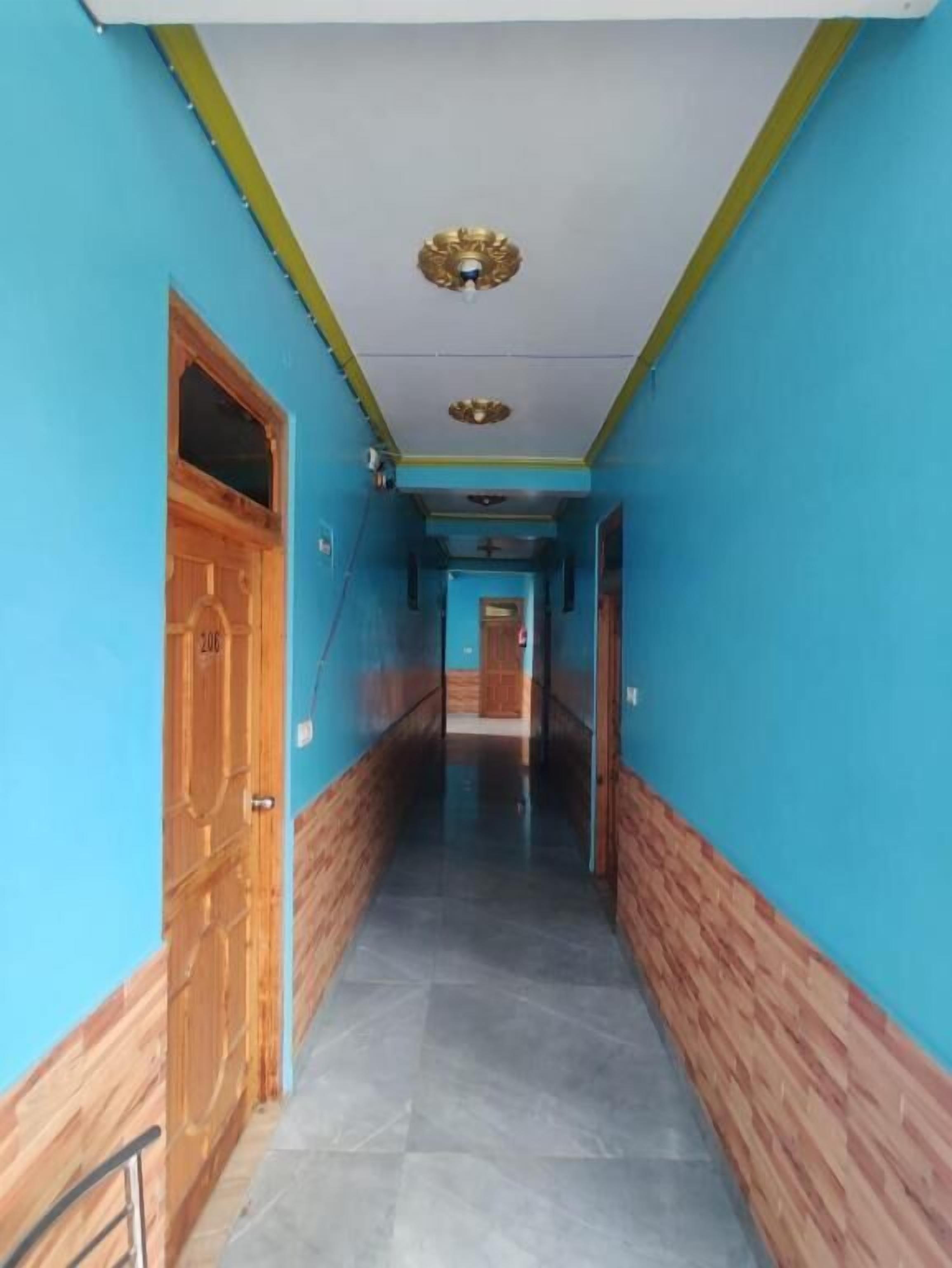 A hallway with blue walls and wooden doors, leading to a room with a tiled floor.