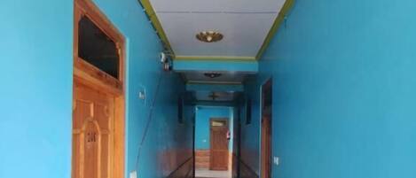 A hallway with blue walls and wooden doors, leading to a room with a tiled floor.
