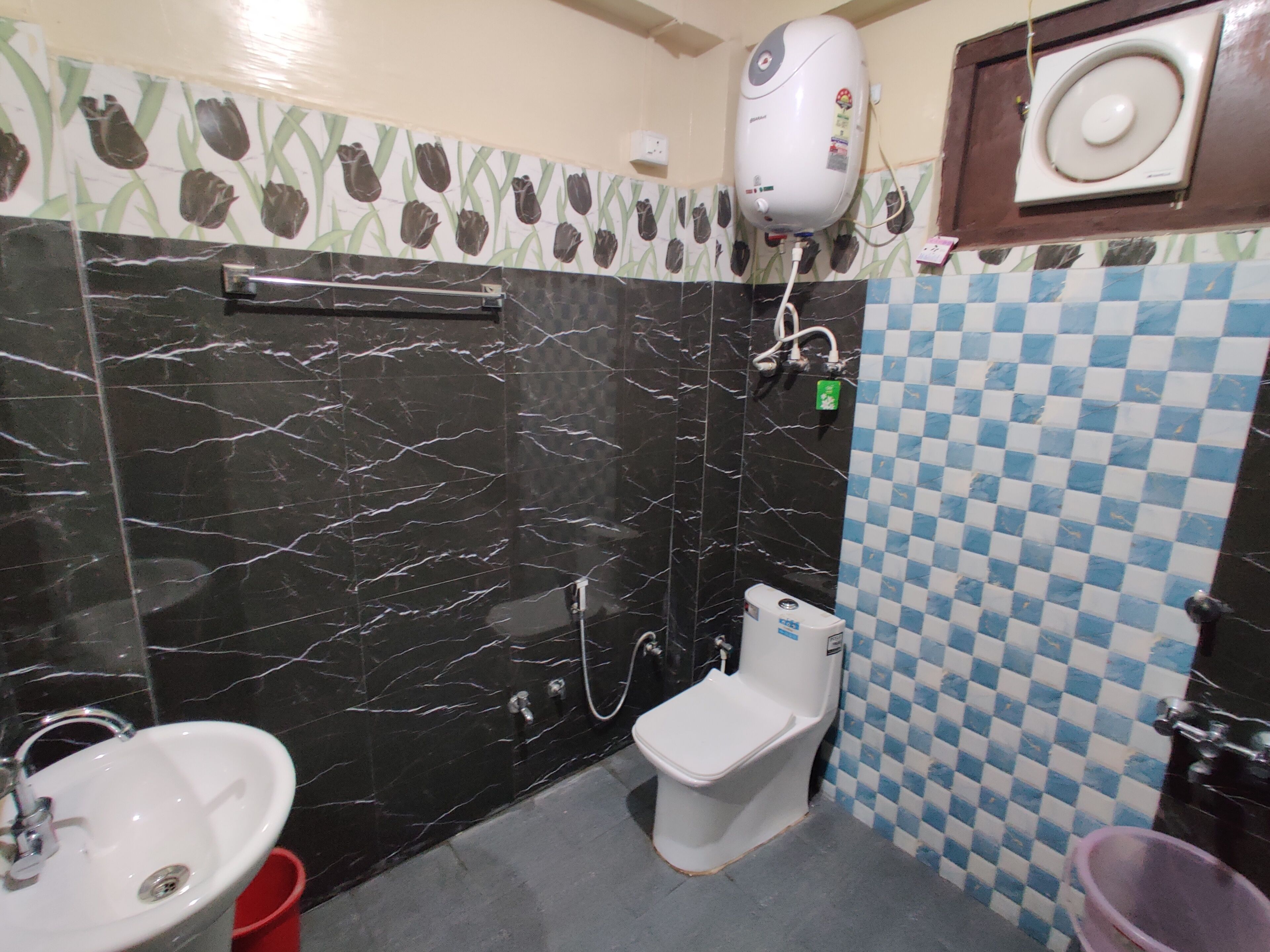 A bathroom with a black marble sink, a white toilet, and a shower area.