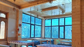 Ein Holzblockhaus-Interieur mit großen Fenstern, einem Marmorboden und mehreren Sitzbereichen.