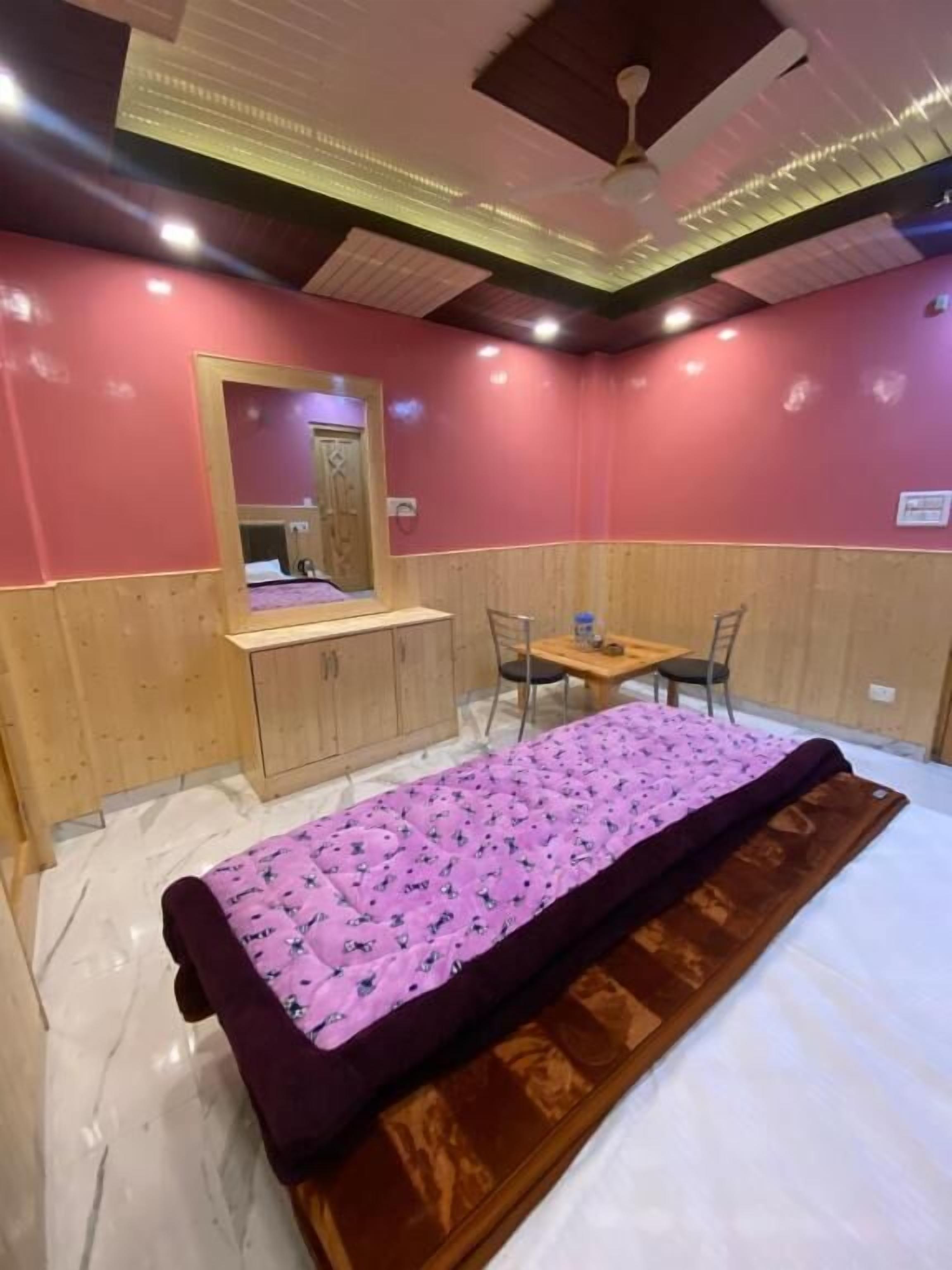 Una habitación con una cama, un escritorio de madera, una silla y un espejo.