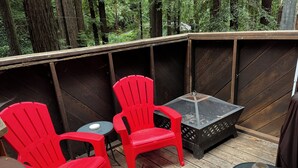 Una terraza con dos sillas Adirondack rojas, una mesita con una vela y un farol decorativo.