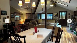 Un comedor acogedor con una mesa dispuesta para dos, sillas de madera y un ordenador portátil sobre la mesa.